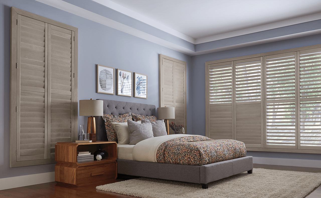 A bedroom with blue wall paint and light gray wall shutters