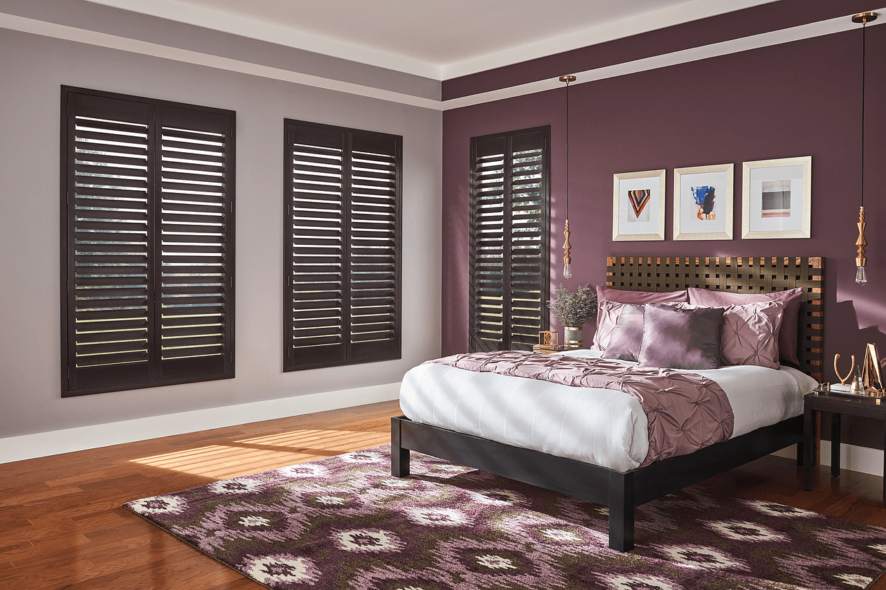 A bedroom with dark brown wood shutters